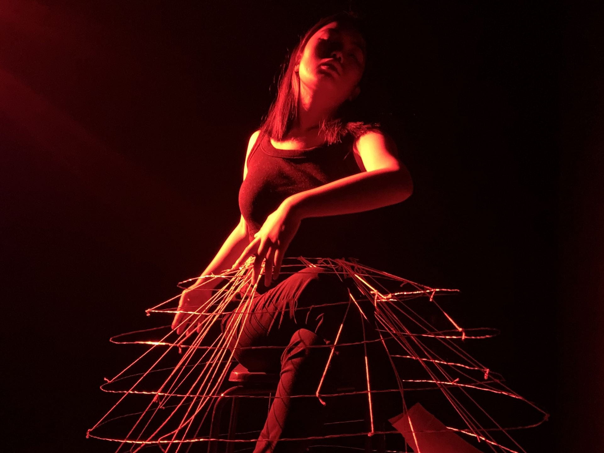 Model wearing a wired framed skirt under red light.