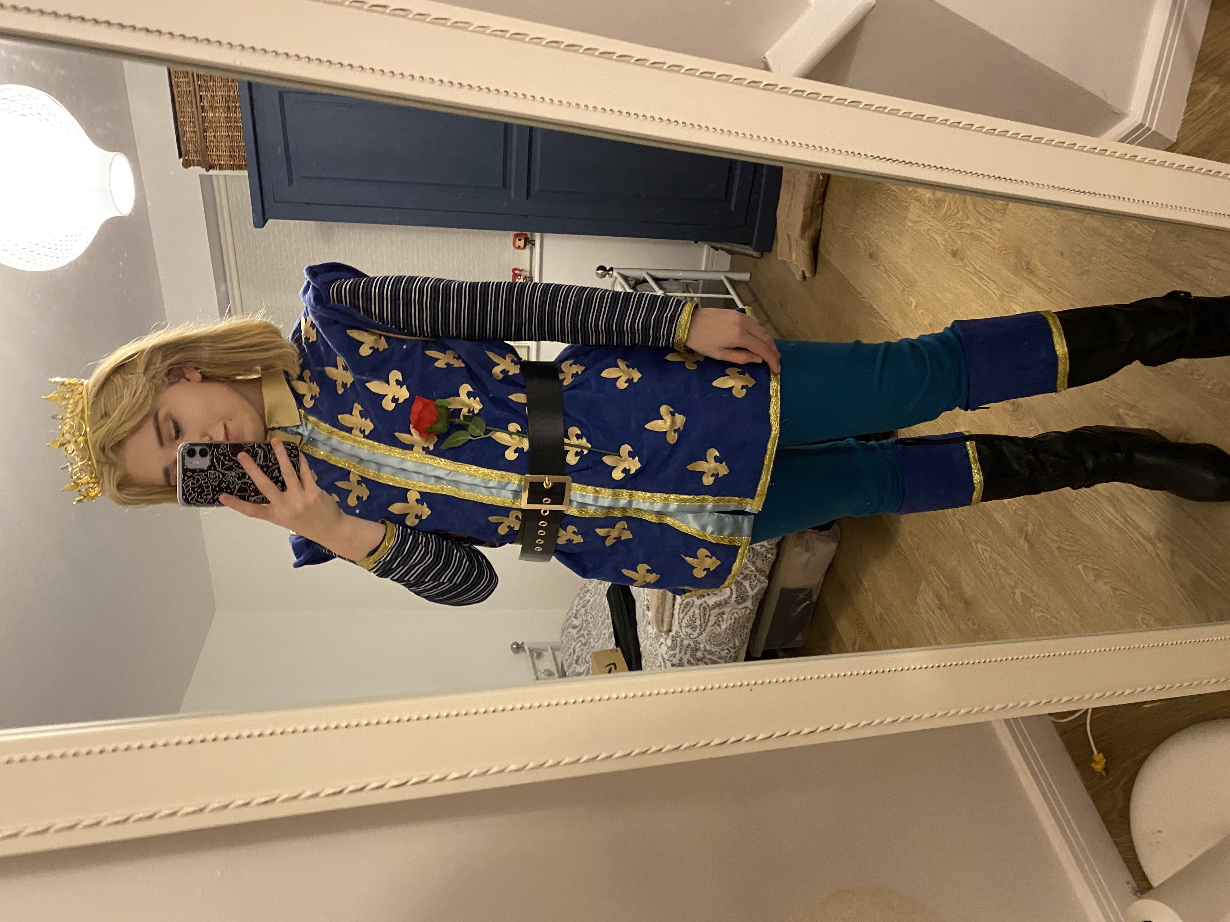 Full image of the blonde wig and gold crown, blue and gold bodice, blue leggings, black boots with a blue and gold trim and a black belt. A fake rose is tucked into the belt.