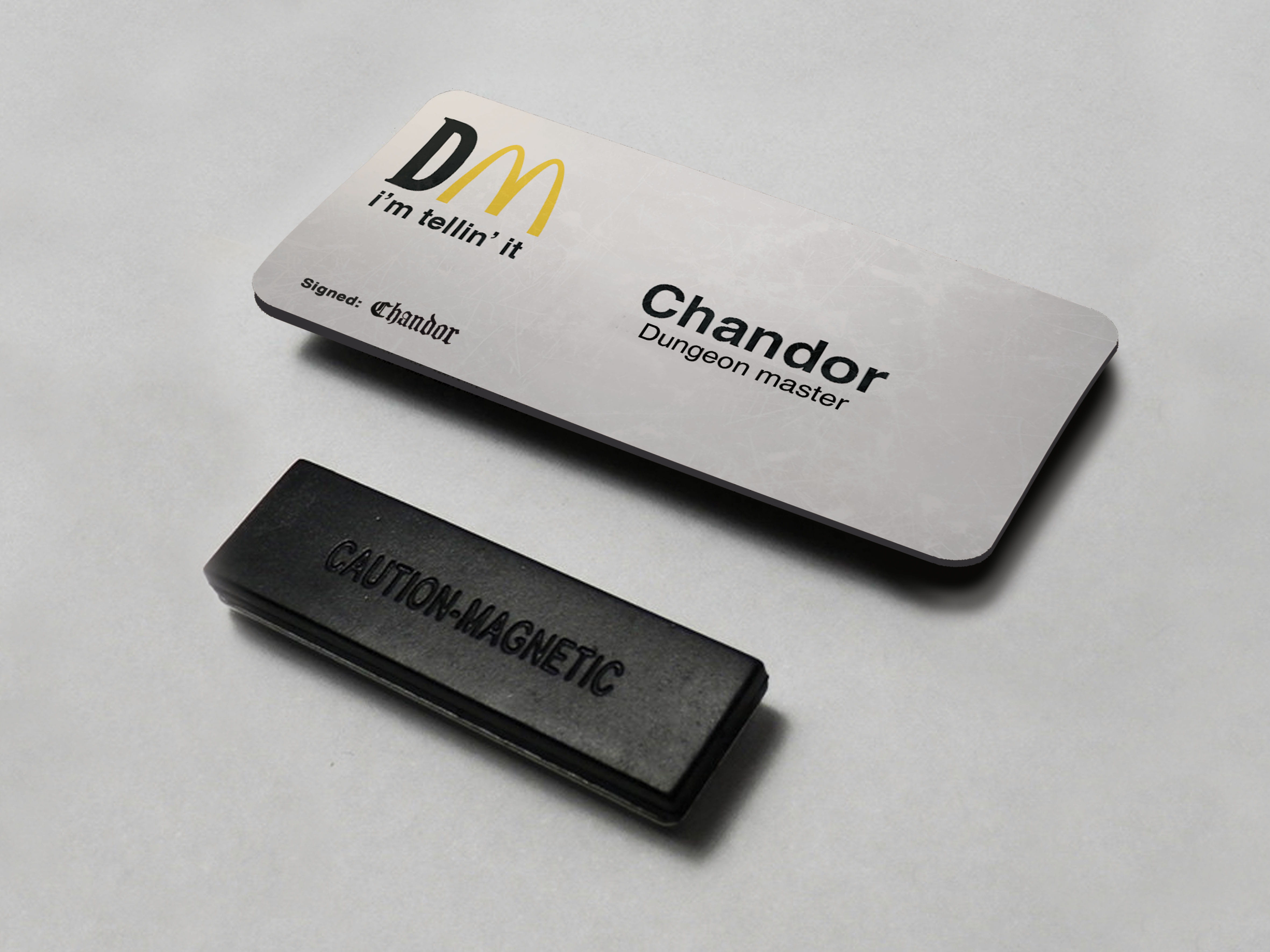 Close-up of a McDonald's name tag. Title reads: 'Chandor, Dungeon Master,'.