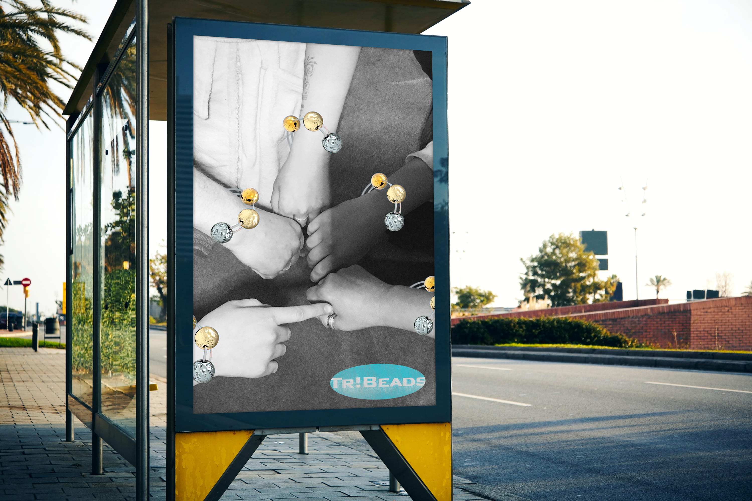 A bus stop advertisement displaying a black & white image of people's hands extended into the centre, with large coloured beads on each of their wrists.