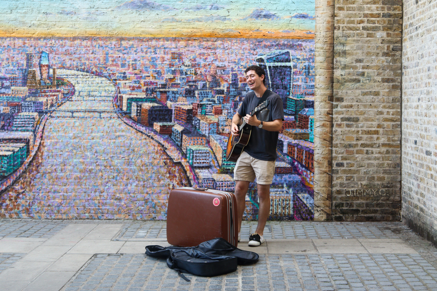 A busker performing in the perfect location as crowds of people pass by, the graffiti art makes the perfect backdrop for his performance.