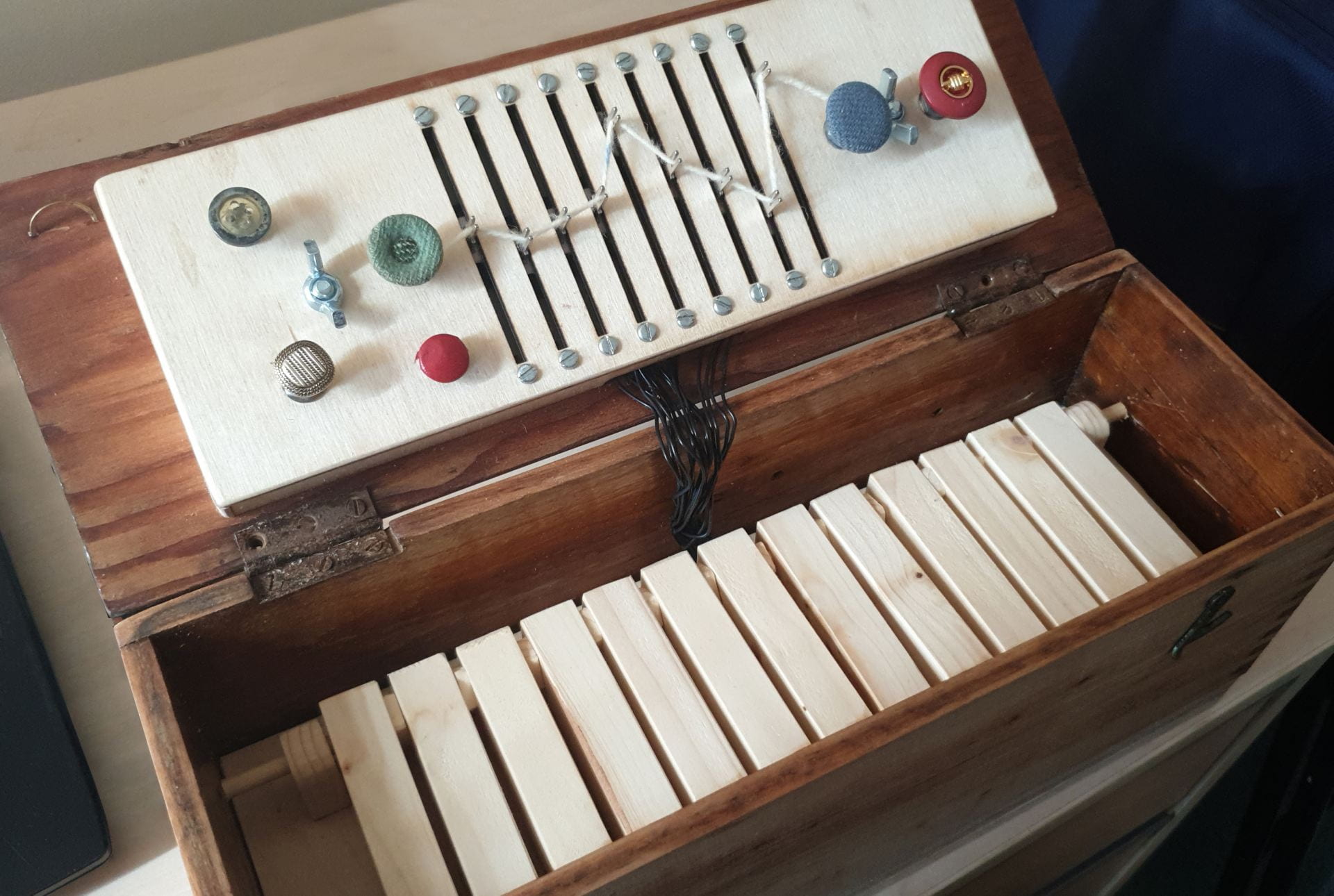 An old wooden box, with a wooden dashboard, and keys connected by wires.