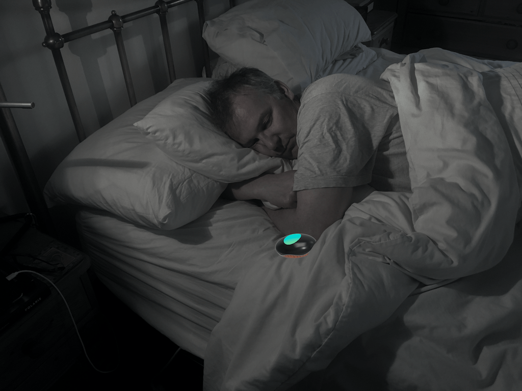 Person lying in bed with the Pebble next to them.