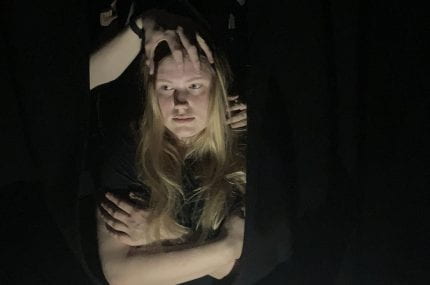 Photograph of woman sat in darkness