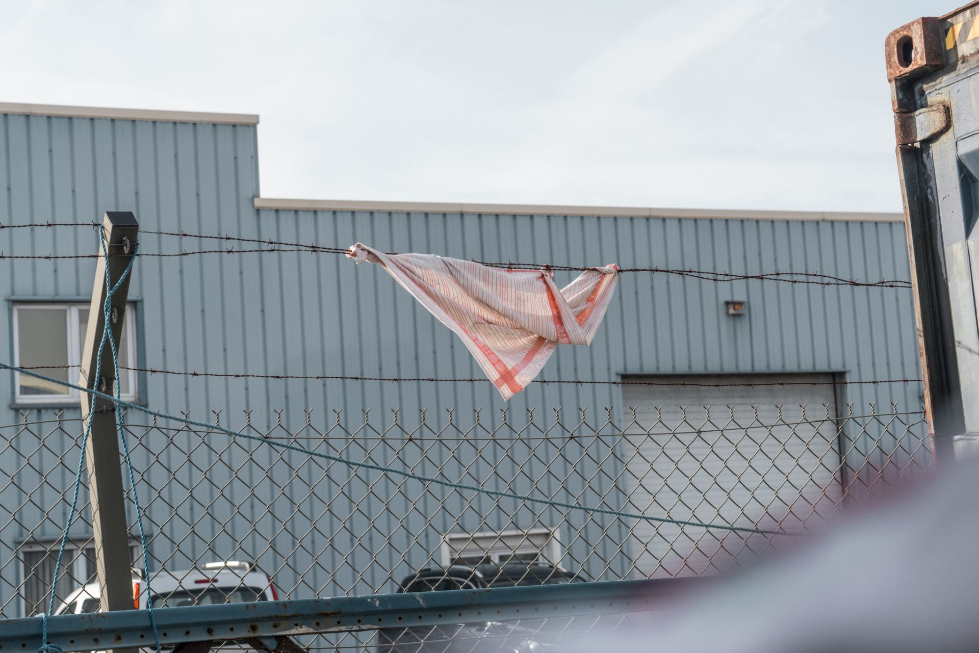 Cloth caught on barbed-wire fence in front of Warehouse.