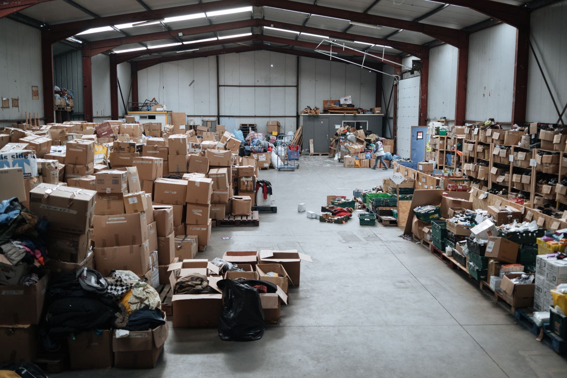 Warehouse interior, stacked cardboard boxes containing a variety of shoes & clothing.