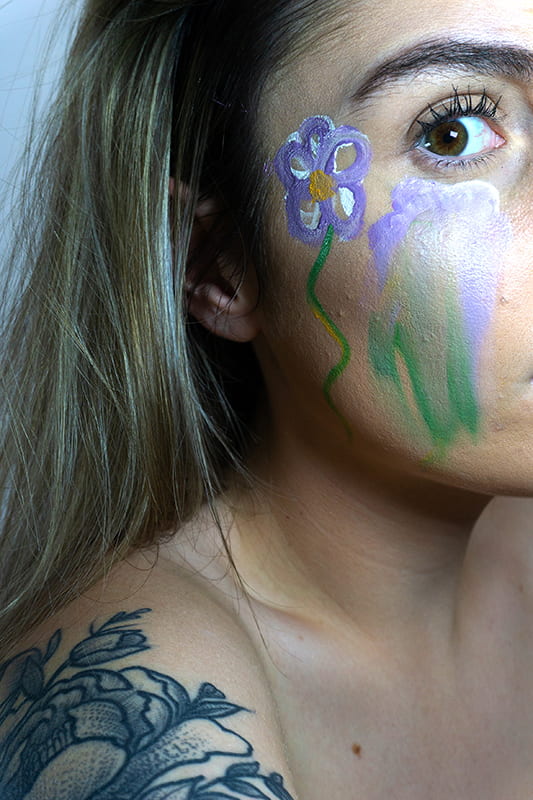 Model with a flower painted on the side of face.