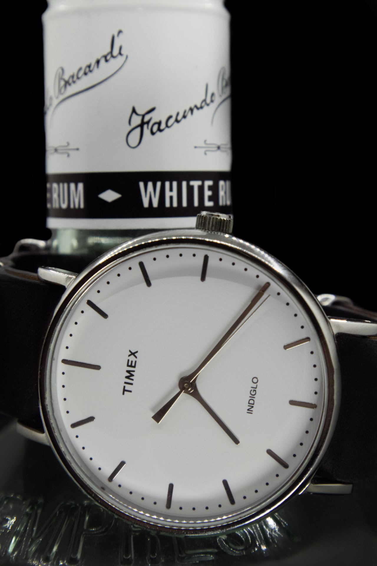 Bottle of rum behind a Timex watch.