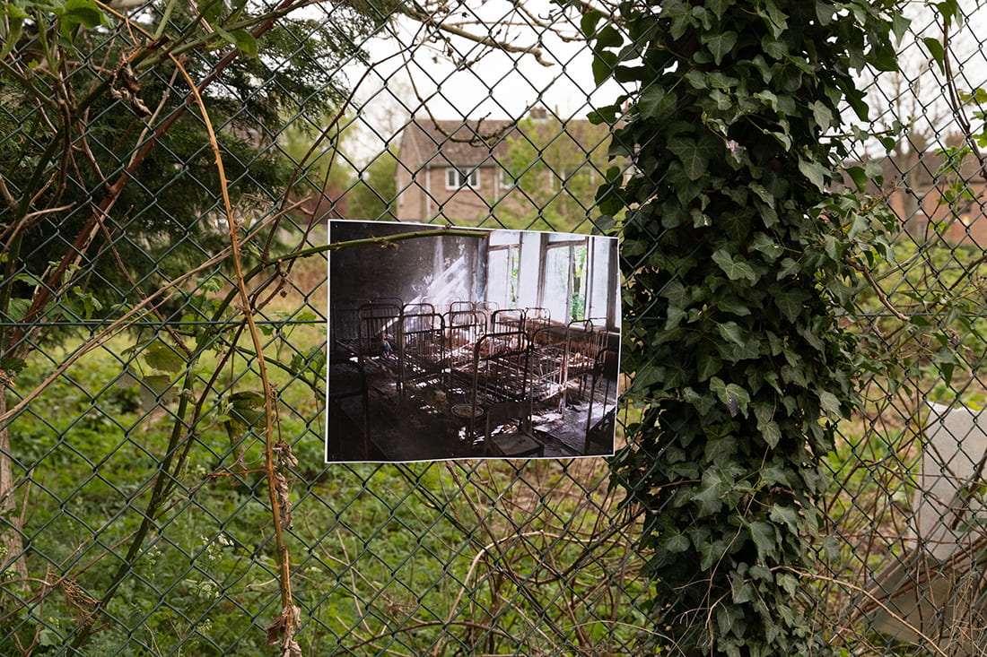 Close-up photograph of metal fencing with a photograph pinned to it.