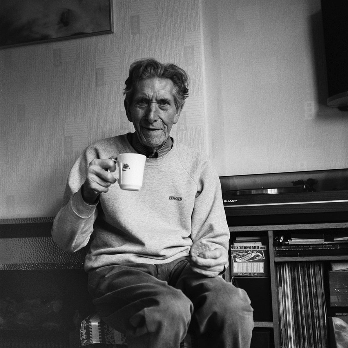 Black and white photograph of man holding a mug.